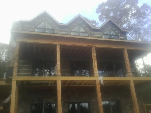 Dormers and porch framing on a large log home under construction — Roof Coating work by our crew in Avera