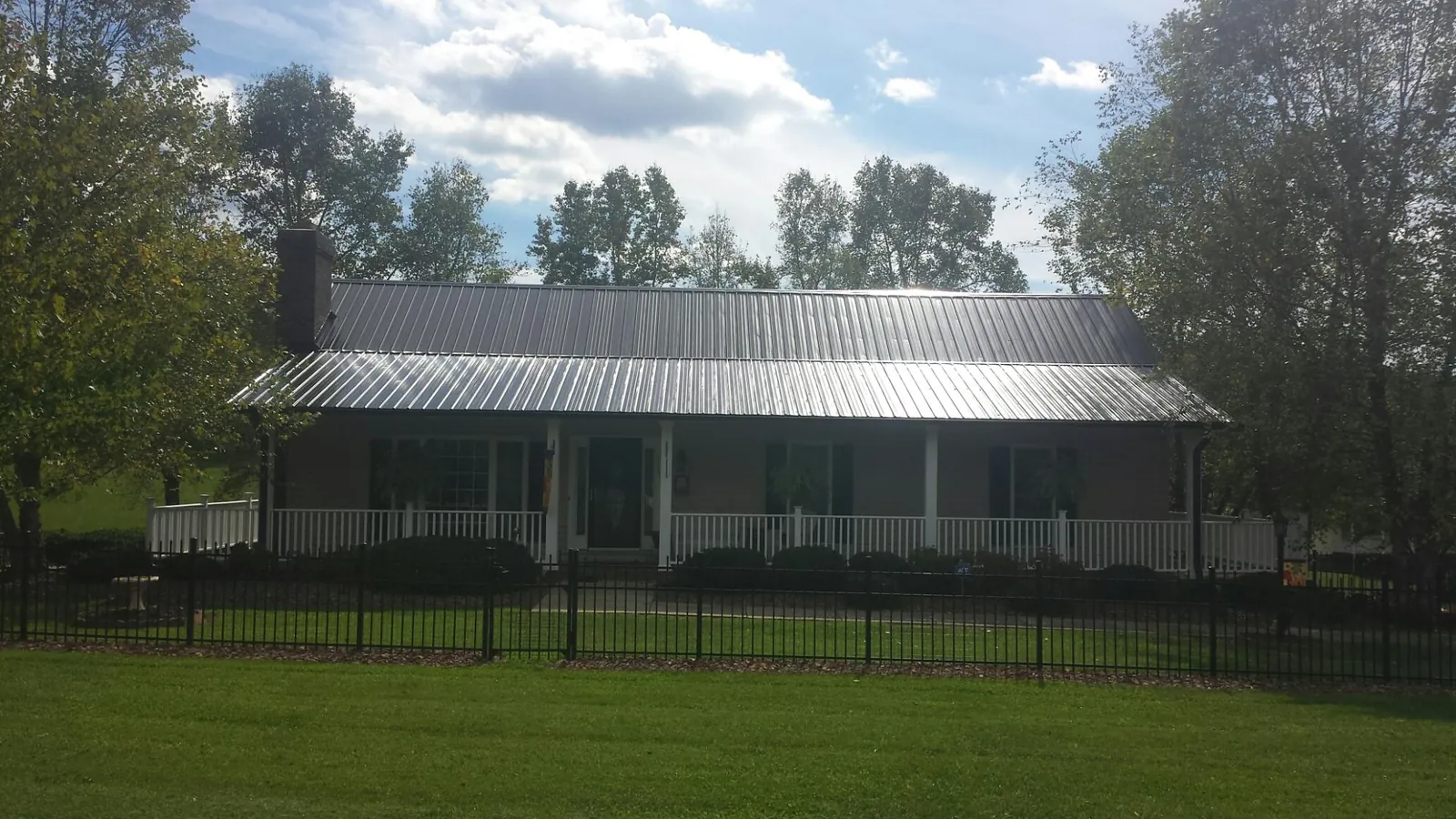 Gray metal roof on a brick ranch with a full width front porch — Gutter Guard Installation work by our crew in Avera
